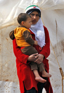 A Syrian refugee carries a baby at Reyhanli refugee camp in Hatay